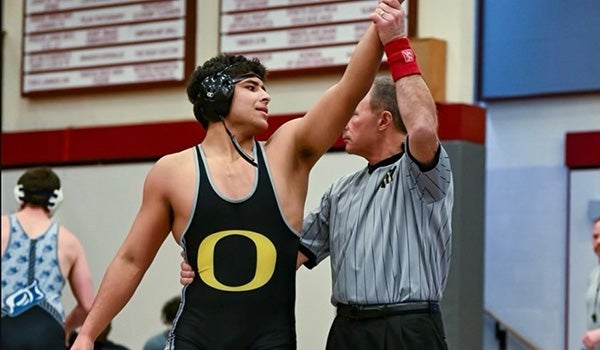 A referee raises the arm of a victorious club wrestler